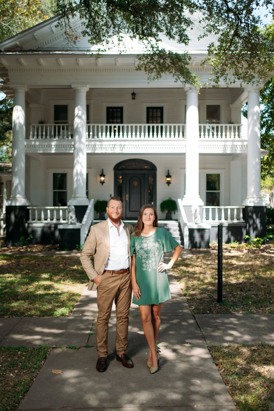 Matt and Liana Walker standing on a sidewalk in front of a white house with columns